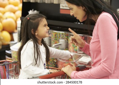 Girl Having Argument With Mother At Candy Counter In Supermarket