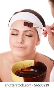 Girl having chocolate facial mask apply by beautician.