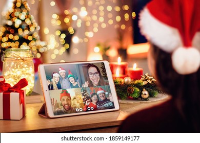 Girl having a Christmas video call with her happy family. Concept of families in quarantine during Christmas because of the coronavirus. Xmas still life with a tablet in a cozy room - Powered by Shutterstock