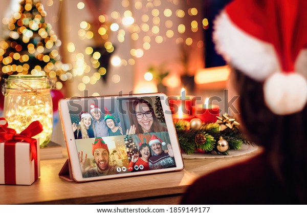 Girl having\
a Christmas video call with her happy family. Concept of families\
in quarantine during Christmas because of the coronavirus. Xmas\
still life with a tablet in a cozy\
room