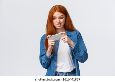 Girl Having Intense Fighting Round In Game, Tap Screen And Trying Beat Friends Score In App. Excited Good-looking Redhead Female Student Wasting Time Playing Smartphone Arcade, White Background