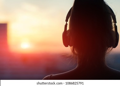 Girl In Headphones Listening To Music In The City At Sunset       