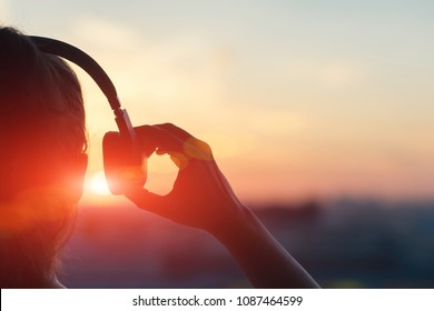 Girl in headphones listening to music in the city at sunset. - Powered by Shutterstock