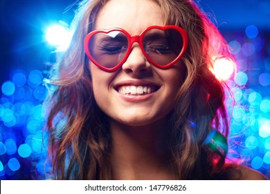 Girl with heart-shaped glasses and closed eyes smiling