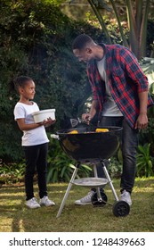 A Girl Helping Her Dad At A Barbecue