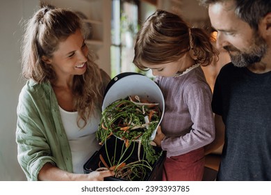 Girl helping parents put kitchen waste, peel and leftover vegetables scraps into kitchen compostable waste. Concept of composting kitchen biodegradable waste. - Powered by Shutterstock