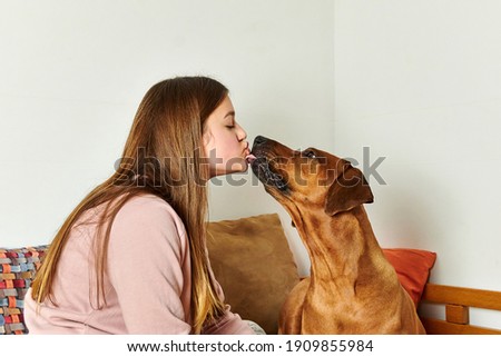 Girl with her dog. Dog kissing owner's face. Girl with her dog at home.