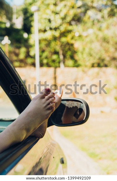 Girl with her\
feet out of the window of the car sunbathing on a summer afternoon,\
while traveling along the\
coast