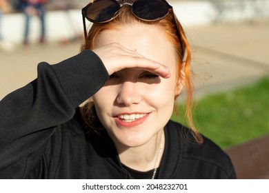 The Girl Hides Her Eyes From The Bright Sun. The Schoolgirl Made A Visor From The Light Out Of Her Hand. The Girl Was Blinded By The Light And She Looks Into The Camera.