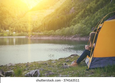 girl hiker in a tent and holding a cup mountains in the background
 - Powered by Shutterstock