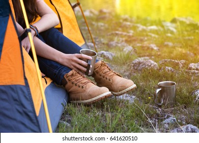 girl hiker in a tent and holding a cup mountains in the background
 - Powered by Shutterstock