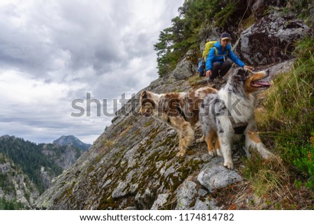 Girl hiking on the edge of a cliff with dogs during a cloudy summer day. Taken in Howe Sound Crest Trail, near Vancouver, BC, Canada.