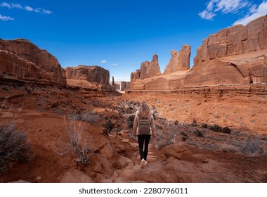 Girl hiking in red mountains in Utah. Woman hiking on Park Avenue area of Arches National Park. Moab Utah, USA