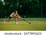 girl hockey player plays field hockey on a sunny day, female hockey player hits the ball with a stick, field hockey concept