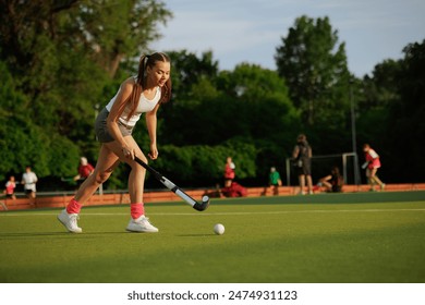 girl hockey player plays field hockey on a sunny day, female hockey player hits the ball with a stick, field hockey concept - Powered by Shutterstock