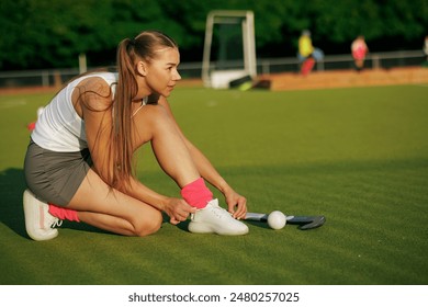 girl hockey player tying sneakers on the field hockey field, concept of playing field hockey, women's sport - Powered by Shutterstock