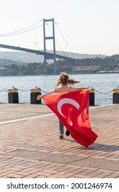 Girl hold Turkish flag near Bosphorus bridge (aka15 July Martyrs Bridge or 15 Temmuz Sehitler Koprusu) in Ortakoy, Istanbul, Turkey. Patriotism. Turkish National Sovereignty and and Children's day.