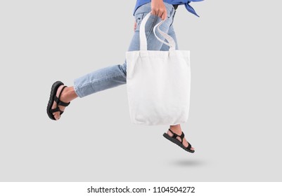 Girl is holding bag canvas fabric for mockup blank template isolated on gray background. 
