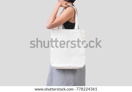 Girl is holding bag canvas fabric for mockup blank template isolated on gray background. 