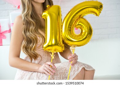 Girl is holding the balls of the number 16. The birthday of sixteen years.