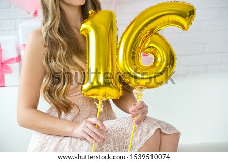 Girl is holding the balls of the number 16. The birthday of sixteen years.