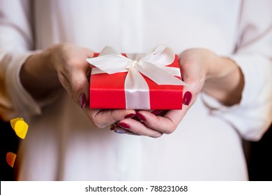 girl holding beautiful  gift for the day valentines day. red box and white bow and bokeh in the background