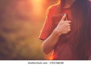 Girl holding a Bible tight as it is the only hope, beautiful warm color palette - Shutterstock ID 1701768238
