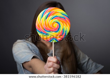 Girl holding big bright candy in front of her 