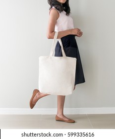 Girl is holding blank canvas tote bag, design mockup. Handmade shopping tote bag for girls.