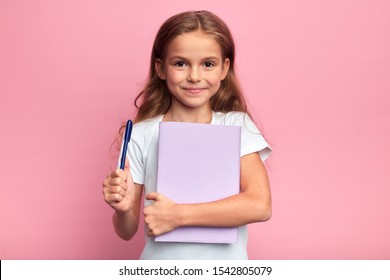 Girl Holding A Book , Pen. Back To School Concept.isolated Pink Background, Studio Shot. Lifestyle, Free Time, Kid Is Ready To Study.