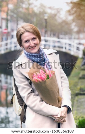 girl holding a bouquet of tulips standing on a street of Amsterdam
