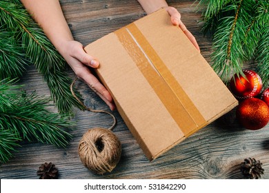 A Girl Holding A Box Over The Table. Parcel Delivery. Christmas Background.