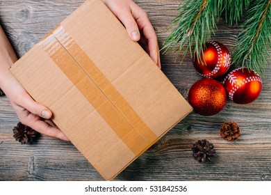 A Girl Holding A Box Over The Table. Parcel Delivery. Christmas Background.