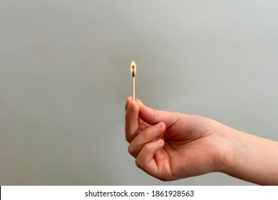 Girl holding a burning match with her hand on a black background, close-up.