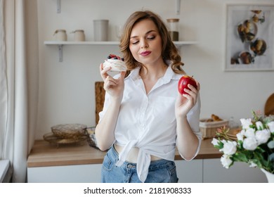 Girl holding a cake in one hand and an apple in the other in the kitchen - Powered by Shutterstock