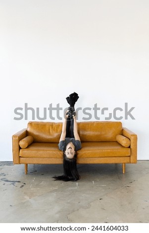 Girl holding canon camera upside down on leather couch