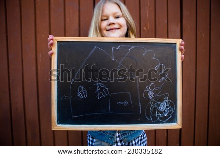 Girl holding a chalkboard with a picture of a house on it