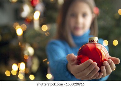 Girl holding Christmas ornament in outstretched hands ภาพถ่ายสต็อก