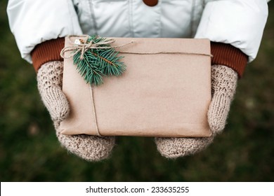 Girl holding a Christmas present in mittens