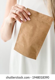 Girl Holding A Craft Package With Tea Or Coffee In Her Hands On A White Background