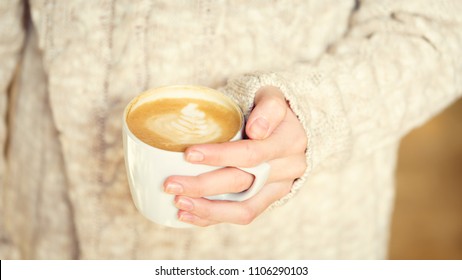 Girl holding a cup of coffee or hot chocolate or chai tea latte. Quiet hygge time concept. Warm tone. Horizontal, wide screen format