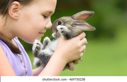 Girl is holding a cute little rabbit, outdoor shoot