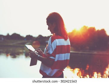 girl holding digital tablet pc at lake shore in sunrise light - Powered by Shutterstock