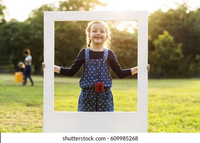 A Girl Is Holding A Frame In A Park