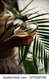 girl holding glass of champagne in bar interior surrounded by palm leaves