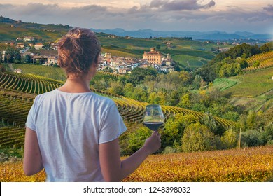 girl holding a glass of red wine looking amazing green vineyards in the italian region of Piedmont, Alba, Barolo town, langhe Monferrato region, Italy