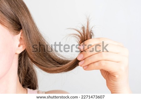 Girl holding her hair with split ends close up on white background.