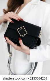 Girl Holding Her Handbag, Close-up. Small Fashionable Women's Leather Clutch Bag With Fabric Strap In Shoe Tone. Girl's Traditional Clutch Bag With Brooch. Handbag Made Of Fine Coloured Genuine Leathe