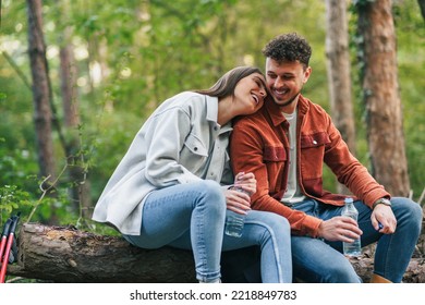 A Girl Is Holding Her Head On His Boyfriend's Shoulder And Smiling, Talking About Something Witty While Sitting At A Branch During Their Nature Exploration.