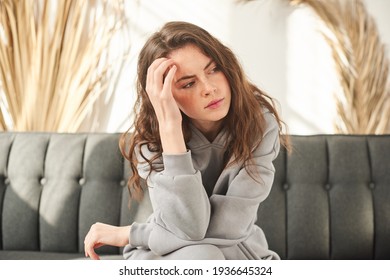 Girl Holding Her Head, Woman Has A Headache. Sad Female Sitting On Couch